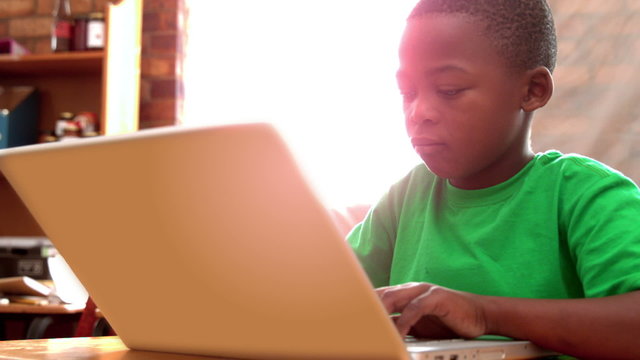 Little boy using laptop in classroom