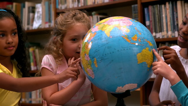 Cute little girls looking at globe in library