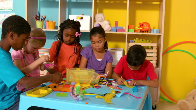 Cute little pupils playing with modelling clay in classroom
