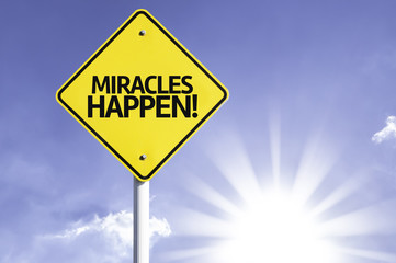 Miracles Happen road sign with sun background