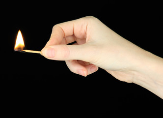 Burning match in female hand, isolated on black