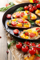 Tasty bruschetta with tomatoes on pan, on old wooden table