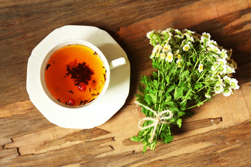 Cup of fresh herbal tea on wooden table
