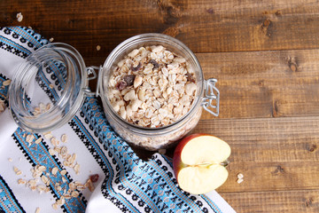 Homemade granola in glass jar, jugs with milk and fresh apple,