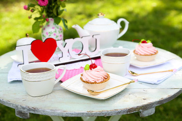 Tasty cake and cup with tea on table, close-up, outdoors