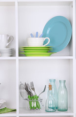 Kitchen utensils and tableware on beautiful white shelves