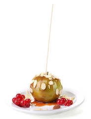 Sweet caramel apple on stick with berries, isolated on white