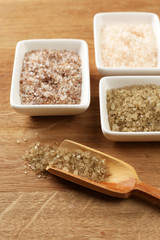 Variety of different sea salt in bowls on wooden table, close
