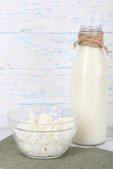 Glass bottle of milk and cottage cheese on wooden background