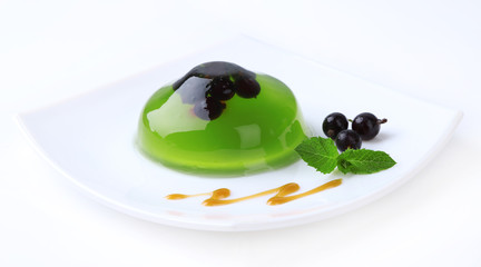 Green jelly with blackcurrant berries and sauce, isolated