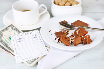 Check, money and remnants of food and drink on table close-up