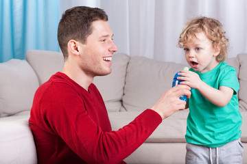 Father giving son a bottle with drink