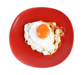 Fried egg on a red plate isolated on white background.