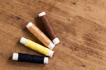 wood Background with sewing tools and colored thread.