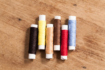 wood Background with sewing tools and colored thread.