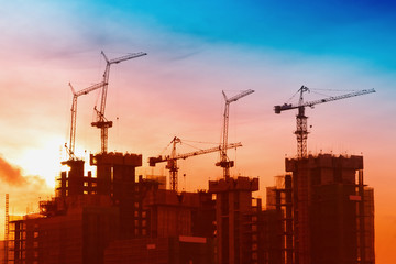 Industrial landscape with silhouettes of cranes on the sunrise b