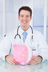 Doctor Holding Piggybank With Bandage In Clinic