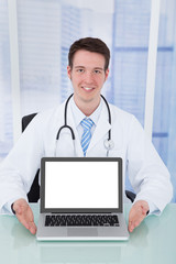 Doctor Presenting Laptop With Blank Screen At Desk