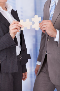 Business People Joining Jigsaw Pieces In Office