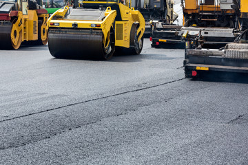 Road roller leveling fresh asphalt pavement