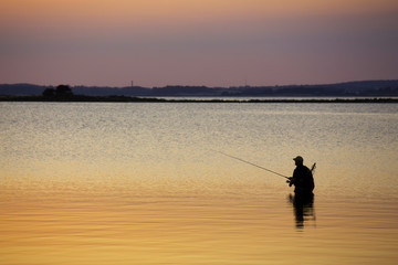 Man standing in water fishing