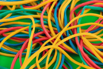 Colorful rubber bands on green background close-up