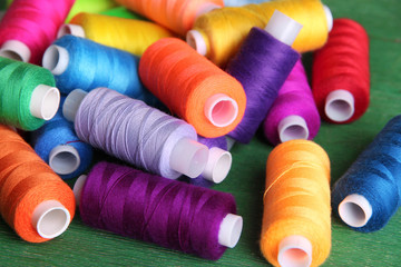 Multicolor sewing threads on wooden background