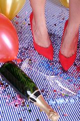 Legs with confetti, champagne and balloons on the floor