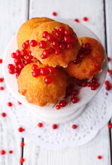 Tasty muffin with red currant berries on color wooden