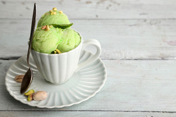 Tasty pistachio ice cream in cup on wooden table