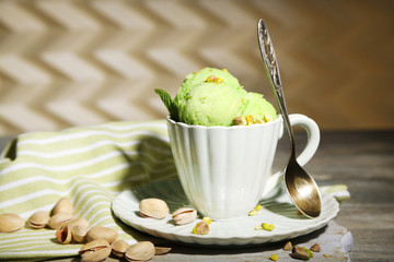 Tasty pistachio ice cream in cup on wooden table