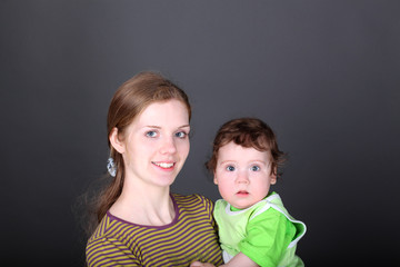 Portrait of happy young mother with cute little son in arms
