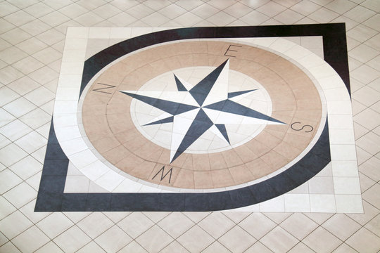 Large compass inlaid with black and light brown tiles on floor