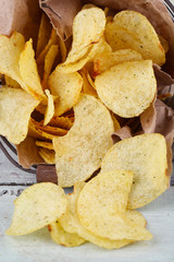 Tasty potato chips in metal basket on wooden table