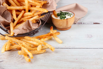 Tasty french fries in metal basket on wooden table