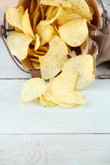 Tasty potato chips in metal basket on wooden table