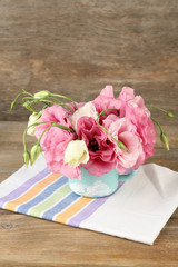 Bouquet of eustoma flowers in vase on wooden background