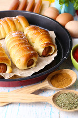 Baked sausage rolls in pan on table close-up