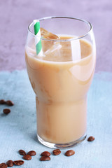 Glass of iced milk coffee on color wooden background