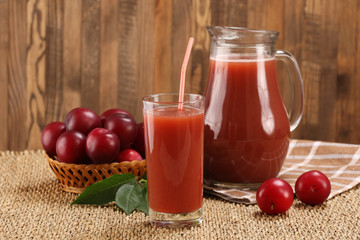 plum juice in a glass and pitcher, plums in a wicker basket on a