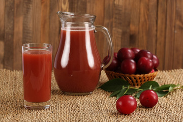 plum juice in a glass and pitcher, plums in a wicker basket