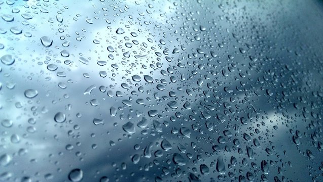 Wet window glass with droplets and blurred rainy sky
