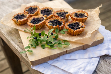 Eight small homemade blueberry pies on wooden table.