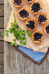 Eight small homemade blueberry pies on wooden table from top.