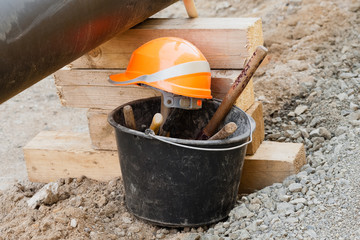 Stillleben auf der Baustelle - Ein Eimer mit Werkzeug und Helm