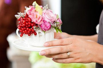 Women's hands holding a cup with flowers and ashberry