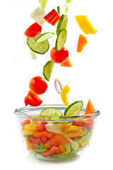 Fresh vegetables falling into the glass bowl