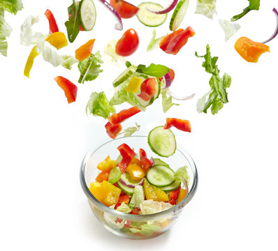 Fresh vegetables falling into the glass bowl
