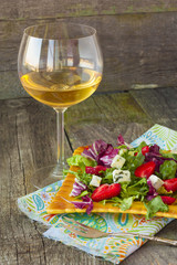 Salad greens, blue cheese and strawberries  close with a glass o