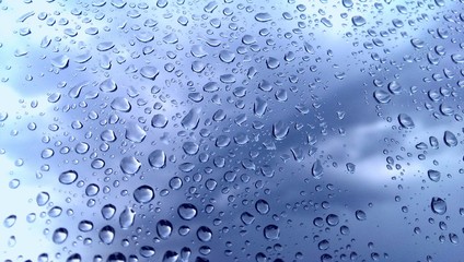 Wet window glass and blurred rainy blue sky